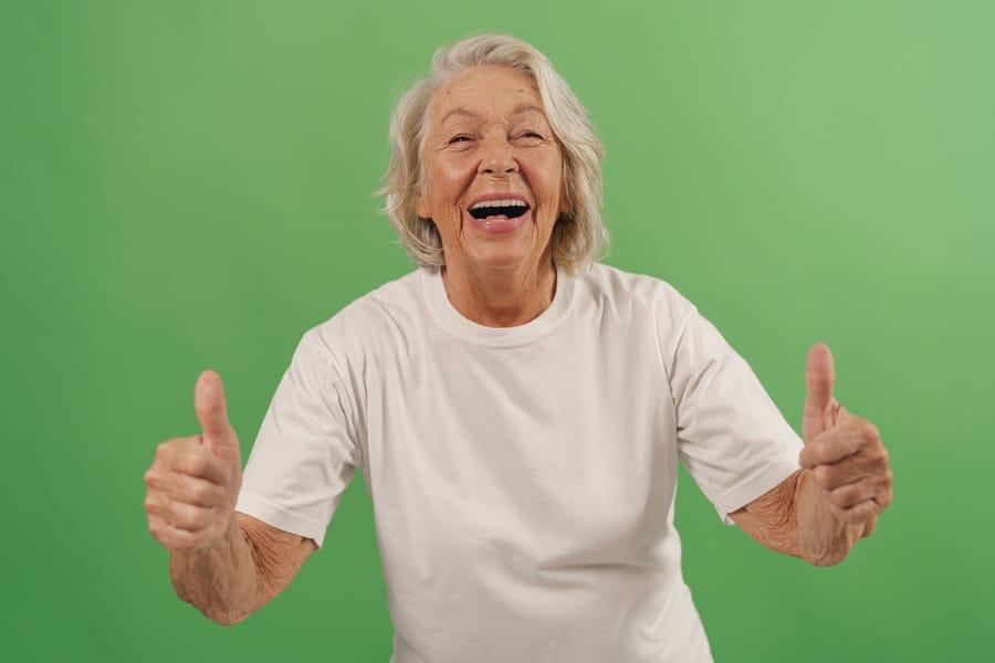 Laughing older woman giving two thumbs up