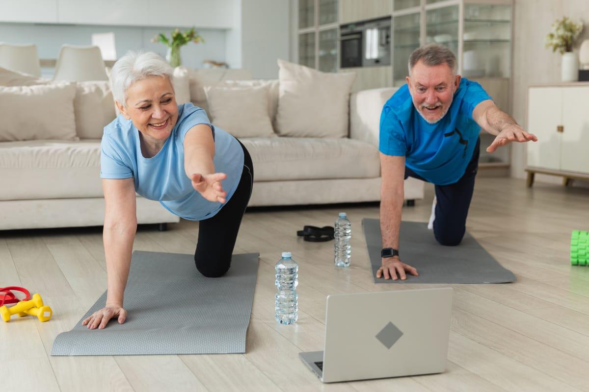 Older couple following a personalized workout on a laptop at home